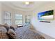 Bright main bedroom features a tray ceiling, ceiling fan, and television mounted on the wall at 9769 Highland Park Pl, Palmetto, FL 34221