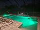 This screened-in pool and spa area with lounge chairs create an inviting backyard oasis at night at 9769 Highland Park Pl, Palmetto, FL 34221