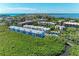 Expansive aerial view of a coastal condo community surrounded by lush greenery with a glimpse of the sparkling ocean at 3607 E Bay Dr # 202, Holmes Beach, FL 34217