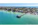 Aerial view showcasing a scenic pier extending into clear turquoise waters, surrounded by charming beachside homes at 3607 E Bay Dr # 202, Holmes Beach, FL 34217
