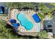 Top-down view of a community pool with lounge chairs and landscaped surroundings, complemented by nearby condos and parking at 3607 E Bay Dr # 202, Holmes Beach, FL 34217