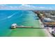 Beautiful aerial view of a pier on a beach with clear turquoise water and a charming beachside community at 3607 E Bay Dr # 202, Holmes Beach, FL 34217
