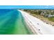 Aerial view of the beach with clear water, soft sand, and distant views of beachfront homes at 3607 E Bay Dr # 202, Holmes Beach, FL 34217