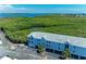 Exterior view of a condo building with covered parking nestled amidst tropical landscaping and waterfront views at 3607 E Bay Dr # 202, Holmes Beach, FL 34217