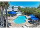 This image captures a community pool with blue umbrellas and multiple lounge chairs for residents to relax and enjoy at 3607 E Bay Dr # 202, Holmes Beach, FL 34217