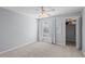 A carpeted bedroom with a ceiling fan, a window with white curtains, and an open closet with folding doors at 4714 Elder Berry Dr, Sarasota, FL 34241