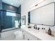 Modern bathroom with blue tile, white vanity, and a glass shower door at 2446 Floyd St, Sarasota, FL 34239