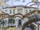 Modern two-story home with a dark gray roof and white facade, partially obscured by tree branches at 2420 Floyd St, Sarasota, FL 34239