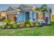 Single-story home with light blue exterior, landscaped yard, and two-car garage at 5415 Limelight Dr, Apollo Beach, FL 33572