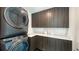 Contemporary laundry room with dark wood cabinets and high-end appliances at 1610 N Lodge Dr, Sarasota, FL 34239