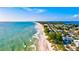 Breathtaking aerial view of a coastline featuring turquoise water, a sandy beach, and lush green vegetation at 105 New Briton Ct, Bradenton, FL 34212