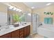 Bathroom featuring double sinks, decorative wall art, tub, and a clear glass enclosed shower to provide functionality and aesthetics at 105 New Briton Ct, Bradenton, FL 34212