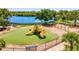 A modern playground with swings and a slide with benches, overlooking a serene lake at 105 New Briton Ct, Bradenton, FL 34212