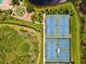 Aerial view of tennis courts near a playground and lake with verdant landscaping around perimeter at 105 New Briton Ct, Bradenton, FL 34212