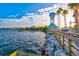 Scenic waterfront view with a clock tower, pier, palm trees, and rocky shoreline under a bright, sunny sky at 105 New Briton Ct, Bradenton, FL 34212