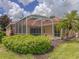 Backyard view of the screened-in lanai featuring tropical landscaping and a view of the home at 3108 Royal Palm Dr, North Port, FL 34288