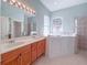 Bright bathroom featuring double sinks, a walk-in shower, and a luxurious soaking tub at 3108 Royal Palm Dr, North Port, FL 34288