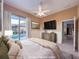 Staged bedroom with a view of the pool, neutral tones, dresser and flat screen TV at 3108 Royal Palm Dr, North Port, FL 34288