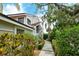 Exterior view of a two-story townhome with a walkway and lush landscaping at 7673 Fairway Woods Dr # 706, Sarasota, FL 34238