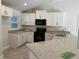 Modern kitchen featuring white cabinets, granite countertops, and black appliances at 8005 Tropicaire Blvd, North Port, FL 34291