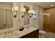 This bright bathroom has dual sinks, marble countertops, sconce lighting, and a glass shower at 221 Evergreen St, Punta Gorda, FL 33982