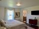 A well-lit bedroom includes a TV, bedside table, area rug, and view into the bathroom at 221 Evergreen St, Punta Gorda, FL 33982
