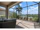 Screened-in patio with comfortable seating and views of the lush landscaping and serene lake at 5709 Puccini St, Nokomis, FL 34275