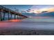 Long pier stretches into the ocean with colorful sunset and moody clouds reflecting on the water's surface at 5709 Puccini St, Nokomis, FL 34275