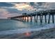 Scenic view of a pier at sunset over the ocean with gentle waves and an American flag at 5709 Puccini St, Nokomis, FL 34275