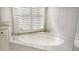 Close-up of an oval soaking tub with marble surround and glass-enclosed shower at 7217 Churston Ln, University Park, FL 34201