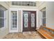 Elegant front entrance showcasing a wooden double door, sidelight windows, a welcome mat, and a bench at 7217 Churston Ln, University Park, FL 34201