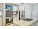 Kitchen featuring marble counters, stainless steel appliances, double oven and kitchen island with stovetop at 7217 Churston Ln, University Park, FL 34201