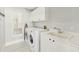 Well-lit laundry room with washer, dryer, sink, and storage cabinets at 7217 Churston Ln, University Park, FL 34201