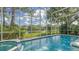 Screened-in pool area with a pool, spa, and tranquil pond view with mature landscaping at 7217 Churston Ln, University Park, FL 34201