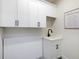 Bright laundry room with white cabinets, a utility sink, and a decorative sign at 2246 Webber St, Sarasota, FL 34239