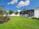 Landscaped backyard with a spacious lawn and screened pool enclosure at 2319 Webber St, Sarasota, FL 34239