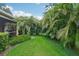 Landscaped backyard with lush tropical plants and grassy area at 4951 Lakescene Pl, Sarasota, FL 34243