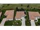 Aerial view of three homes with tile roofs, lush landscaping, and a community pool at 6772 Greenview Ln, Englewood, FL 34224