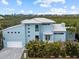 Modern two-story home showcasing a light blue exterior, metal roof, and lush landscaping at 705 Jungle Queen Way, Longboat Key, FL 34228