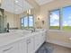 Modern bathroom with double vanity, large mirror, and tranquil water views at 705 Jungle Queen Way, Longboat Key, FL 34228