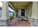 Relaxing front porch with brick pavers, two wicker chairs, and stone columns at 17006 Hampton Falls Ter, Lakewood Ranch, FL 34202