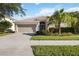 House with a two-car garage, palm trees, and a green lawn at 9009 Kingsbury Pl, Bradenton, FL 34212