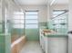 Retro bathroom with light green tile, shower, and sink at 7665 Sanderling Rd, Sarasota, FL 34242