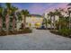 Stunning white house with a gravel driveway, lush landscaping, and a solar panel system at 7665 Sanderling Rd, Sarasota, FL 34242