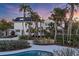 White house with solar panels, palm trees, and pool at sunset at 7665 Sanderling Rd, Sarasota, FL 34242