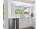Modern white kitchen with stainless steel appliances and terrazzo floors at 7665 Sanderling Rd, Sarasota, FL 34242