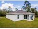 White house with gray roof, covered patio, and grassy yard at 1702 Rada Ln, North Port, FL 34288