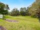 Expansive grassy backyard with mature trees and garden at 5050 Kestral Park S Way, Sarasota, FL 34231