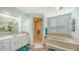 Tranquil bathroom featuring dual vanities, a separate glass-enclosed shower, and a luxurious soaking tub at 56 Broadmoor Ln, Rotonda West, FL 33947