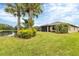 Landscaped backyard with grassy lawn, palm trees, and view of lake at 6912 Gosport Cv, Lakewood Ranch, FL 34202